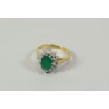 AN EMERALD & DIAMOND FLORAL RING, in 9ct yellow gold and composed of an oval emerald and twelve