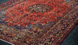 A RED GROUND PERSIAN KASHAN CARPET with traditional medallion design, 382 x 298cms