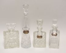 FOUR CUT-GLASS DECANTERS, three with silver labels