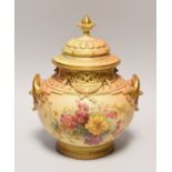 A ROYAL WORCESTER PORCELAIN BLUSH VASE of ornate moulded form with twin-handles and finial picked