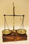 A SET OF 1920s AVERY BRASS PILLAR SCALES on a wooden base with single long drawer, the pans of