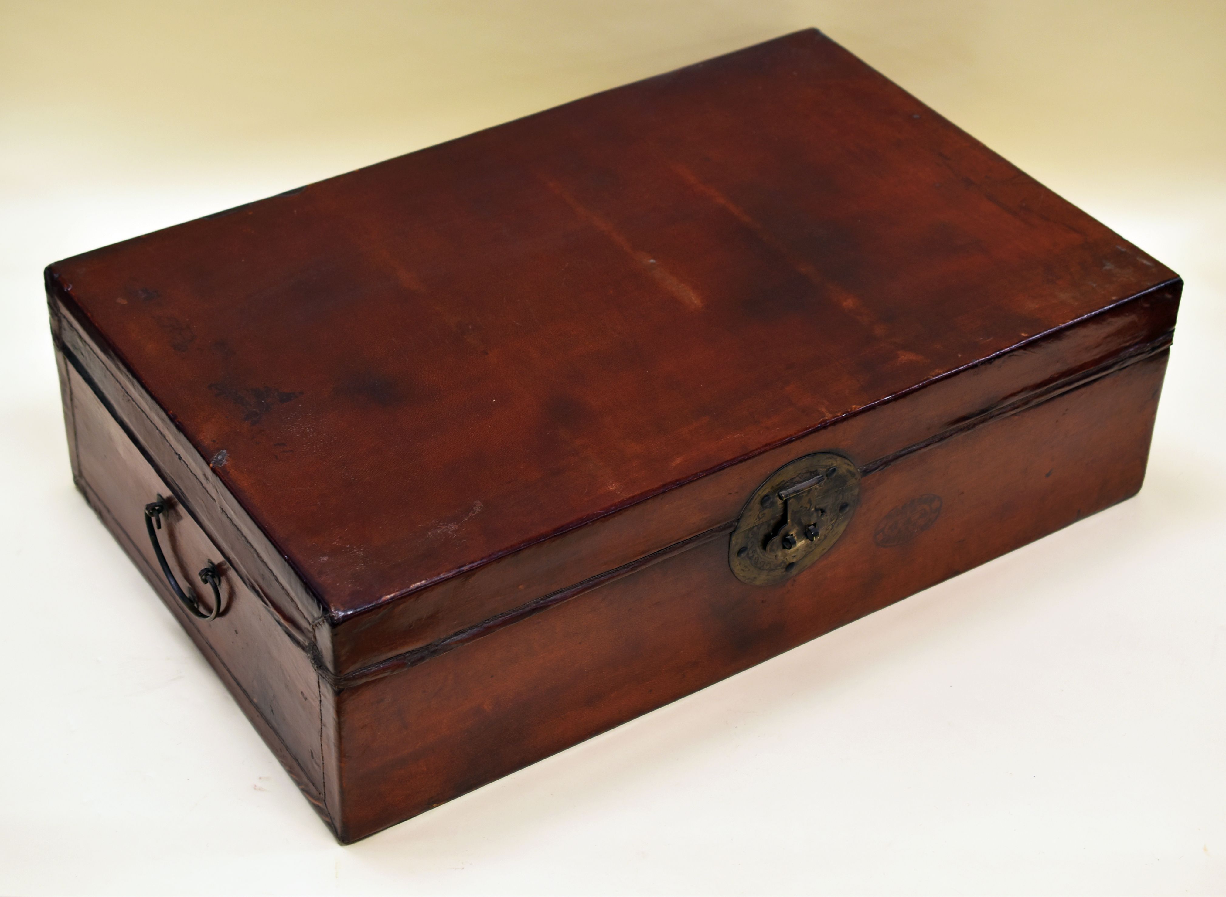 A CHINESE TRUNK IN PIG-SKIN LEATHER with two handles and printed interior, 76cms wide