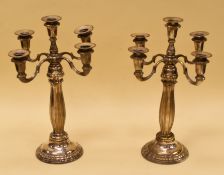 A PAIR OF CONTINENTAL FOUR-BRANCH CANDELABRA on circular bases with raised decoration, 48cms high