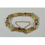 A 9CT CELTIC LINK BRACELET set with eight green and purple jewels, 10gms