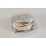 A SILVER CLAM SHAPED RING BOX having a hammered lid hinging to reveal a purple velvet cushion