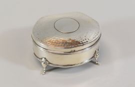 A SILVER CLAM SHAPED RING BOX having a hammered lid hinging to reveal a purple velvet cushion