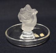 A LALIQUE GLASS DISH having a raised centre pedestal in the form of two figures clutching a