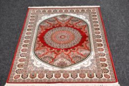 A RED GROUND WOVEN SILK IRANIAN RUG with traditional design, 174 x 120cms