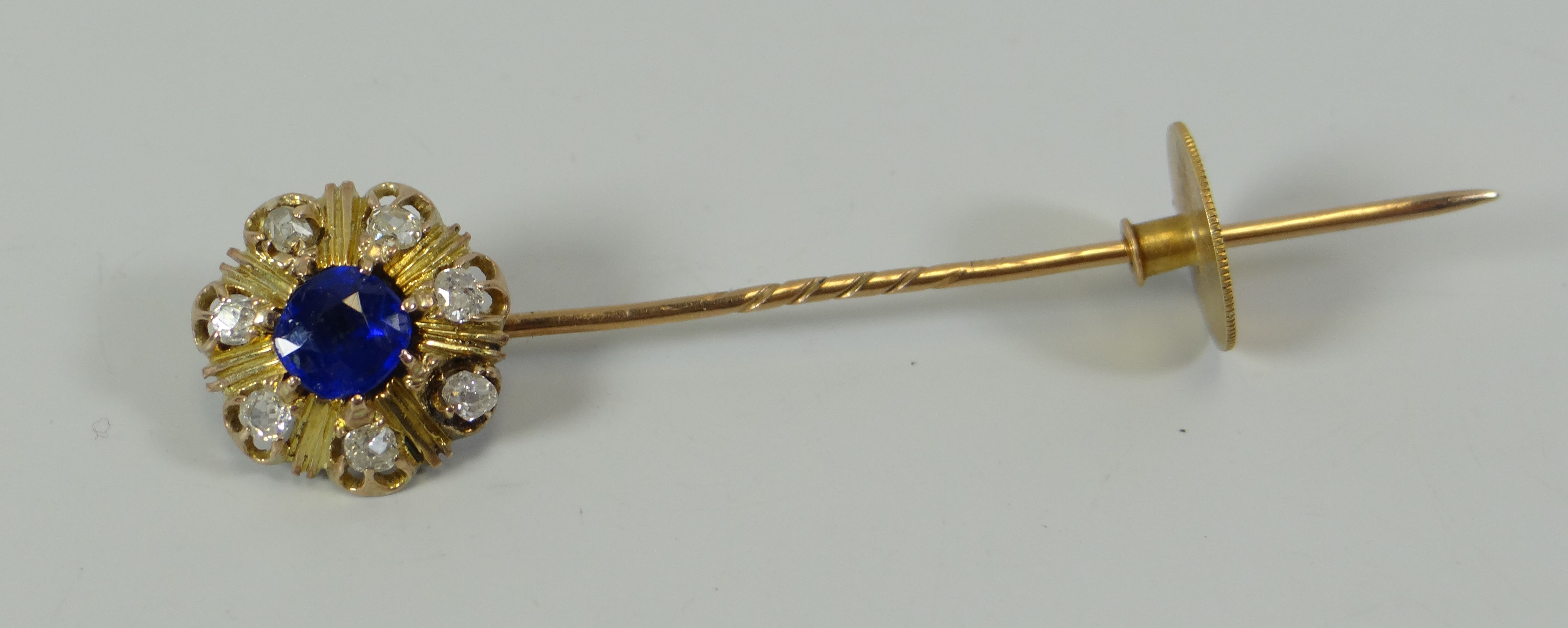 A BELIEVED 18CT GOLD DIAMOND & SAPPHIRE TIE-PIN composed of centre sapphire and seven outer old-mine