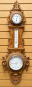 AN EARLY TWENTIETH CENTURY ANEROID BAROMETER the oak case heavily carved with floral and foliate