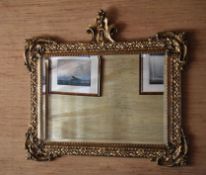 A REPRODUCTION ELABORATE GILT FRAMED MIRROR with bevelled glass and floral frame, 104cms high