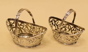 A PAIR OF SILVER PIERCED BON-BON BASKETS of oval bonnet form with swing handles, Birmingham 1903,