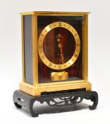 A JAEGER LECOULTRE ATMOS CLOCK with red marble effect face and side panels, brass chapter ring