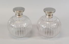 A PAIR OF SILVER TOPPED GLASS SCENT BOTTLES, having machine-turned and monogrammed lids hinging to