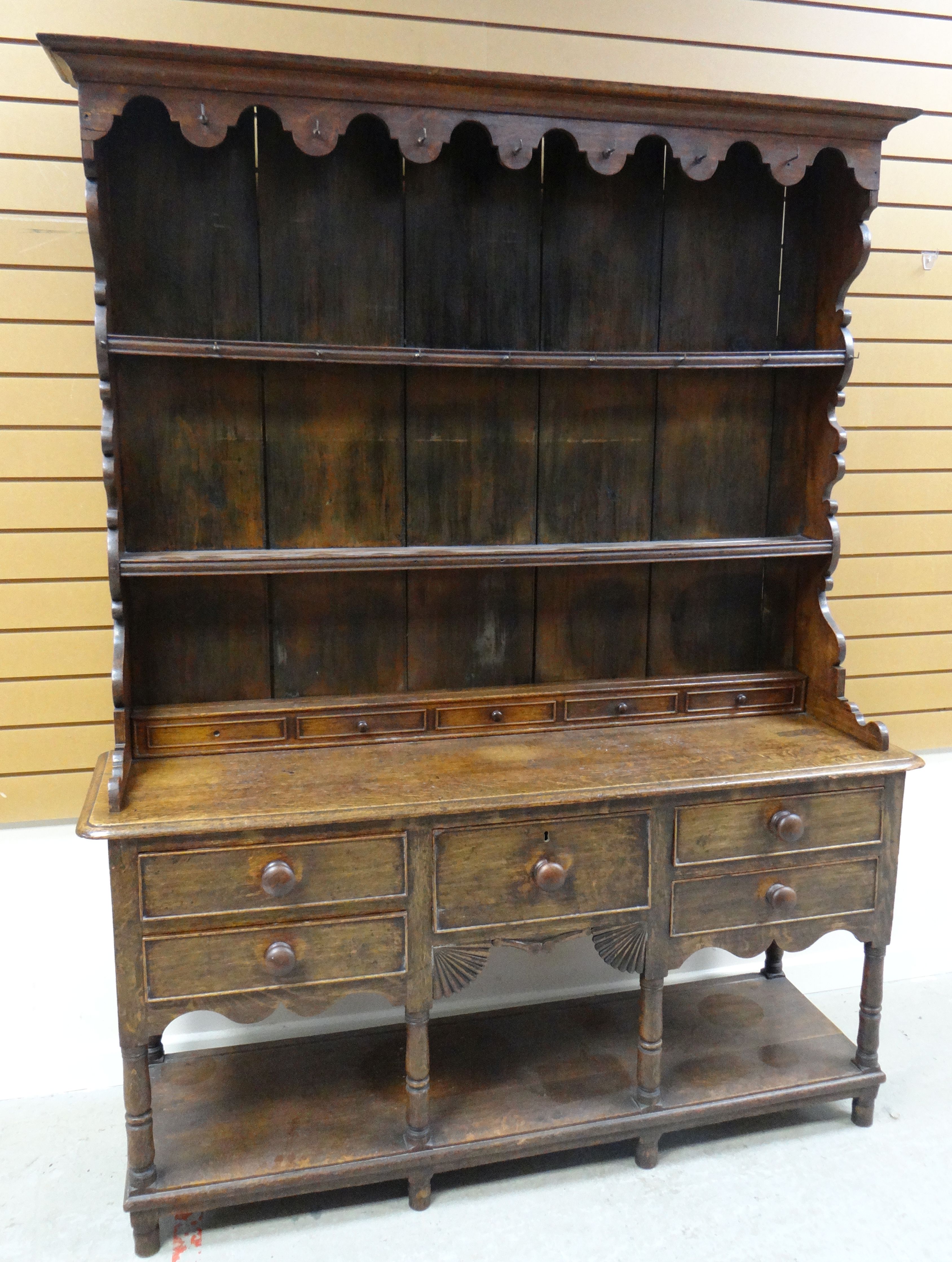 AN OAK WELSH DRESSER BASE with a good borded rack with two shelves, shaped sides and with old hooks,