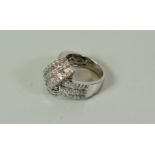 A MODERN 18CT WHITE GOLD DIAMOND CLUSTER RING of folded ribbon design with nine rows of small