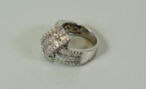 A MODERN 18CT WHITE GOLD DIAMOND CLUSTER RING of folded ribbon design with nine rows of small
