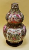 A FAMILLE ROSE GOURD VASE, twentieth century, with all round decoration and panels, on wooden stand,