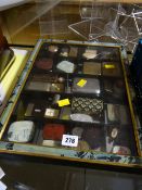 A framed table top cabinet containing numerous vintage commercial packaging tins etc