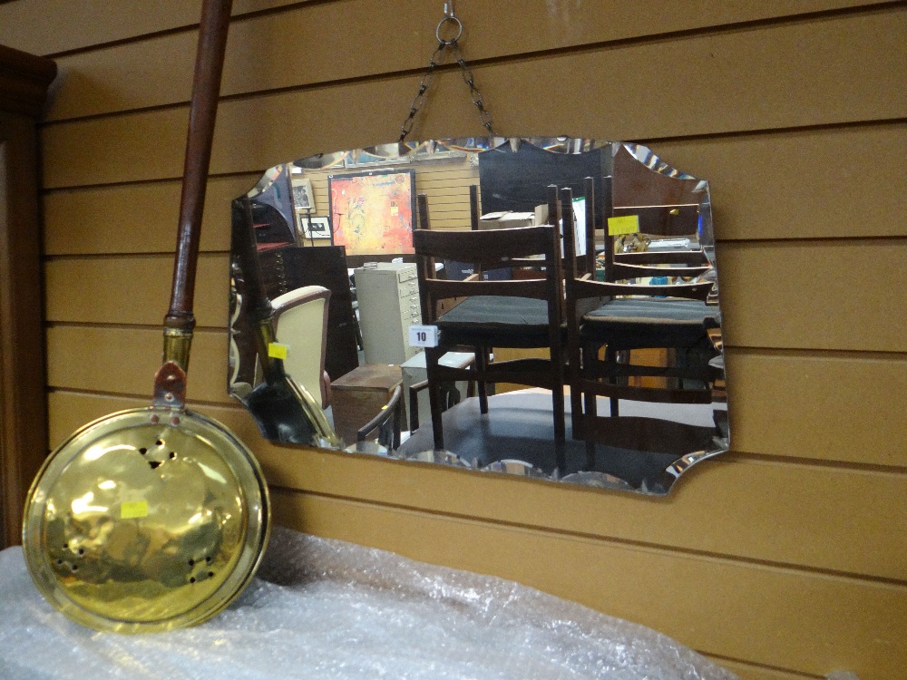 A vintage wall mirror with fancy bevelled edge and an antique bed warming pan