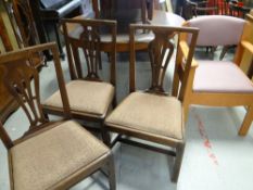 A trio of comb back farmhouse chairs together with a modern office-style chair