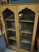 A vintage oak two-door glazed bookcase together with a small oak nursing chair with Art Nouveau tap