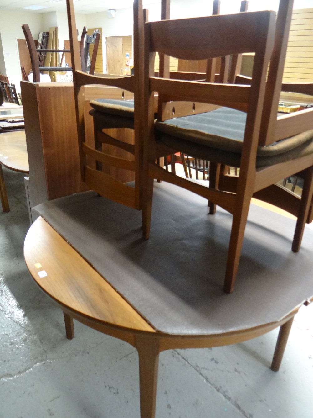 A circular Nathan Suite extending dining table and four chairs and matching bookcase