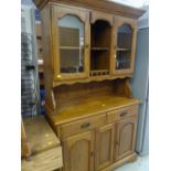 A dark stained pine kitchen dresser with glazed cupboard top and two-drawer two-cupboard base