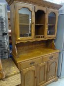 A dark stained pine kitchen dresser with glazed cupboard top and two-drawer two-cupboard base
