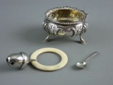 A VICTORIAN SILVER SALT and a 1920's baby's rattle, the circular salt with floral decoration in