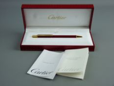 A CARTIER STYLO BILLE MUST II RED LACQUER BALLPOINT PEN, no. 593002 with original booklets
