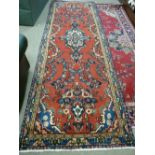 A FULL PILE RED GROUND PERSIAN RUNNER with floral medallion design, 300 x 100 cms