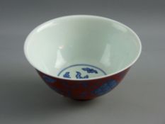 A CHINESE CORAL GROUND PORCELAIN BOWL decorated with underglazed blue mythical lions having