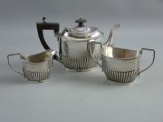 A THREE PIECE SILVER BACHELOR TEA SERVICE of oval form with half fluted decoration, 14 troy ozs