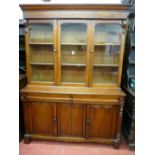 A VICTORIAN MAHOGANY THREE DOOR BOOKCASE having a shaped crown over twin glazed doors and central