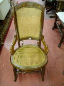 A CIRCA 1900 WALNUT ROCKING CHAIR, the top rail with burr walnut decoration, cane work back and seat