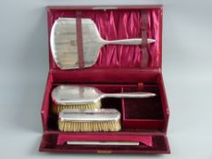 A CASED HALLMARKED SILVER FOUR PIECE DRESSING TABLE SET of hand mirror, brushes and comb, Birmingham