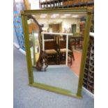 A REPRODUCTION REGENCY STYLE OVERMANTEL MIRROR in green and gilt livery, 124 cms high, 96 cms wide