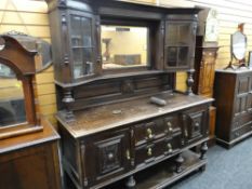 An antique carved sideboard with raised base having two drawers, two cupboards and with a semi