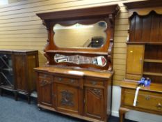 A carved Edwardian mirror back sideboard with cupboards and three drawers to the base