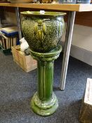 A green pottery planter on stand