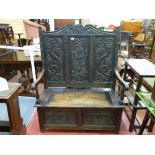 A HIGHBACK CARVED OAK BOX SEAT BENCH, the triple panel back with shaped top rail and mythical