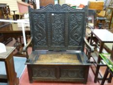 A HIGHBACK CARVED OAK BOX SEAT BENCH, the triple panel back with shaped top rail and mythical