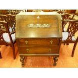 A 1930's OAK FALL FRONT BUREAU, the slope fall with carved front decoration, interior writing