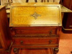 A 1930's OAK FALL FRONT BUREAU having carved front decoration, pierced drop handles on reeded
