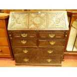 AN ANTIQUE CARVED OAK FALL FRONT BUREAU, the slope fall with leaf and floral carved panels,