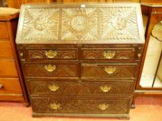 AN ANTIQUE CARVED OAK FALL FRONT BUREAU, the slope fall with leaf and floral carved panels,