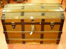 A VINTAGE DOME TOPPED TRAVEL TRUNK with wood and metal banding, leather carry handles marked 'M