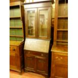 A VINTAGE OAK BUREAU BOOKCASE with twin glazed upper doors above a sloped fall front, single base