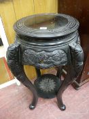 A CHINESE EBONIZED HARDWOOD STAND with circular top and carved lower detail and under tier shelf, 76